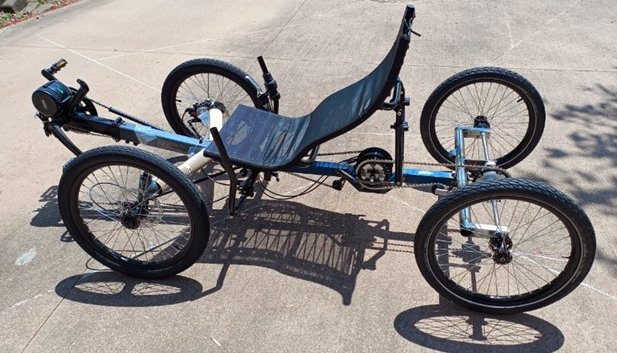 Recumbent cargo quad cycle parked on driveway.